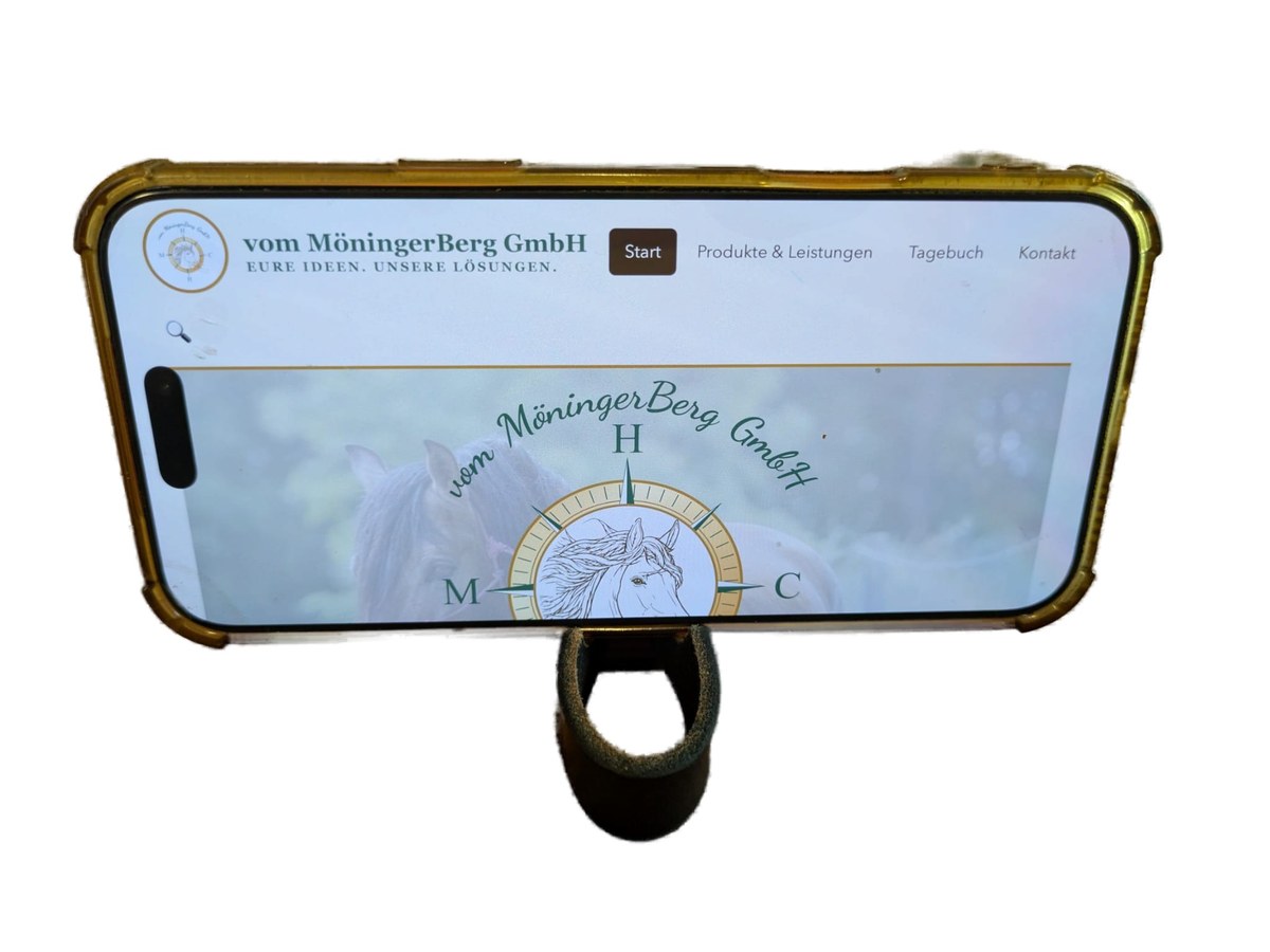 Schlüsselanhänger aus Leder mit integrierter Handyhalterung, hält ein Handy aufrecht mit geöffneter Webseite vom MöningerBerg
